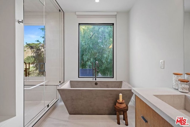 bathroom with tile patterned flooring, vanity, and a bath