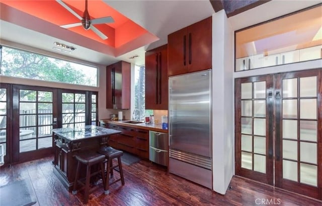 kitchen with dark hardwood / wood-style flooring, a kitchen bar, stainless steel appliances, and french doors