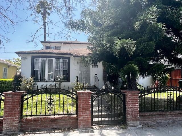 8656 Cadillac Ave, Los Angeles, CA 90034 - view of property hidden behind natural elements featuring stucco siding, a gate, and a fenced front yard