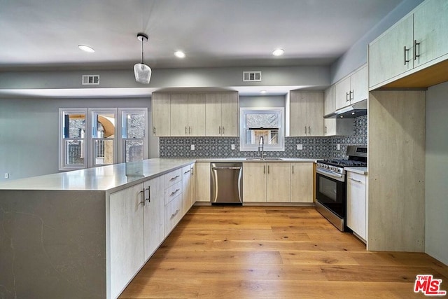 kitchen featuring sink, decorative light fixtures, stainless steel appliances, light wood-type flooring, and decorative backsplash