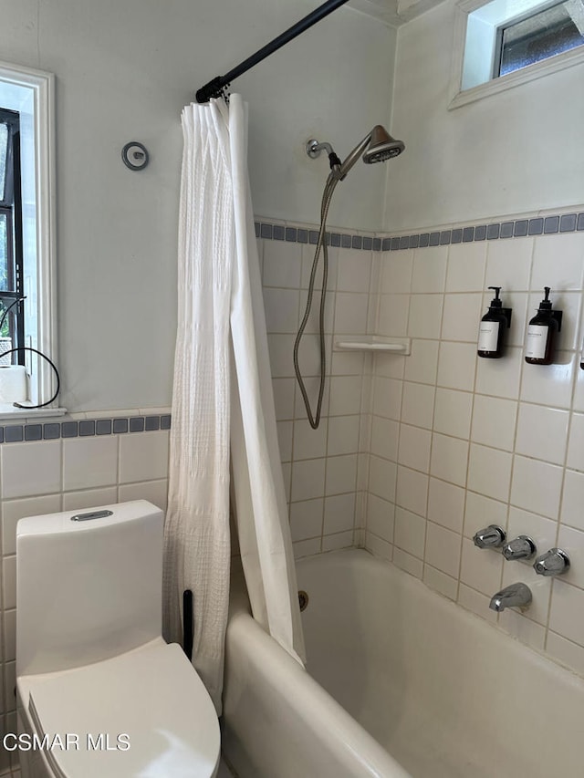 bathroom with shower / tub combo with curtain, toilet, tile walls, and a healthy amount of sunlight