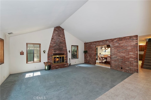 unfurnished living room featuring a brick fireplace, brick wall, carpet, and high vaulted ceiling