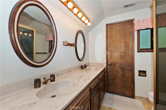 bathroom with lofted ceiling, a textured ceiling, vanity, and toilet