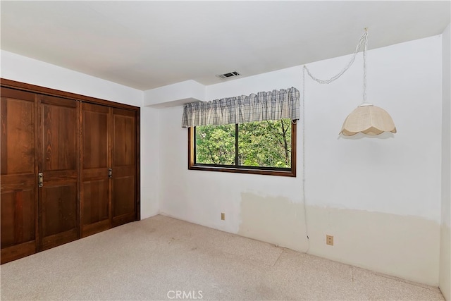 unfurnished bedroom with light colored carpet and a closet