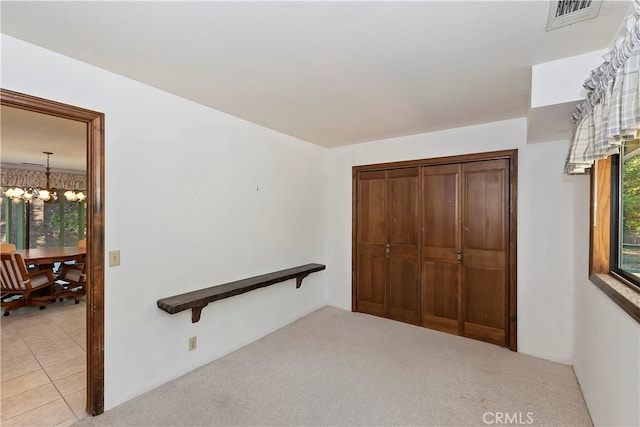 hall with light carpet and an inviting chandelier