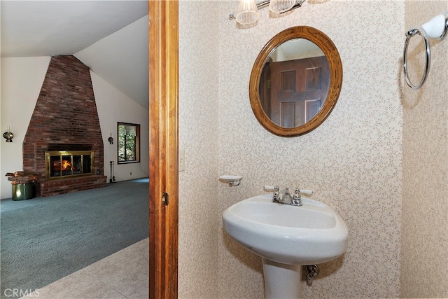 bathroom featuring lofted ceiling, a fireplace, and sink