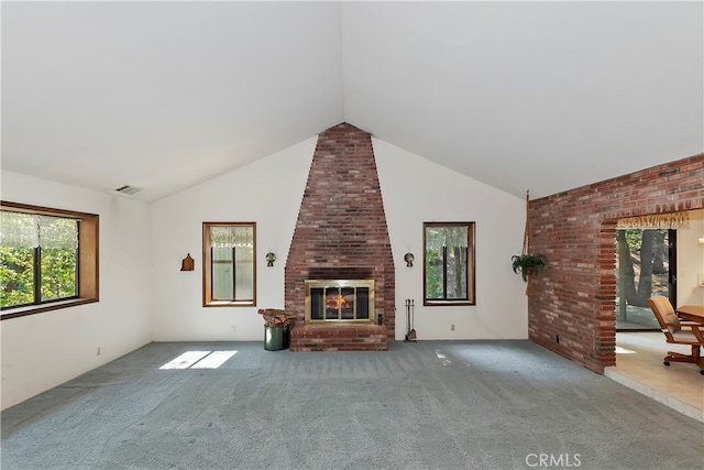 unfurnished living room featuring a brick fireplace, vaulted ceiling, light colored carpet, and a wealth of natural light