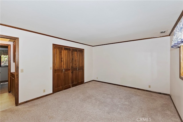 unfurnished bedroom featuring light carpet, a closet, and ornamental molding