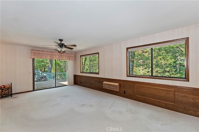 unfurnished room featuring light carpet, ceiling fan, and a wall mounted air conditioner