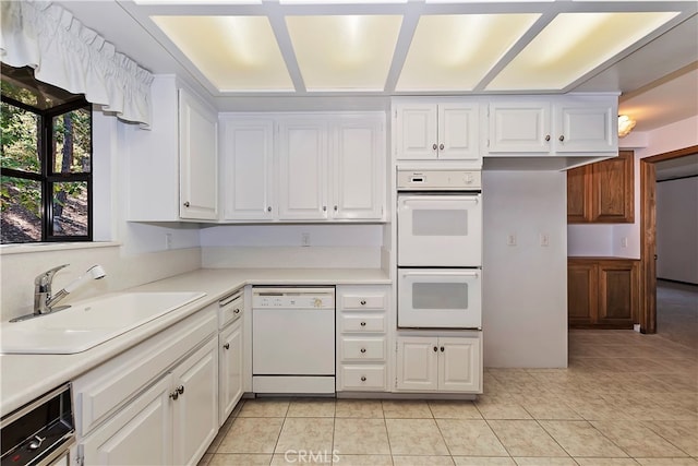 kitchen featuring white appliances, sink, light tile patterned floors, and white cabinets