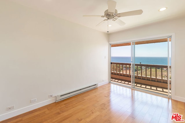 unfurnished room with light hardwood / wood-style flooring, a water view, ceiling fan, and baseboard heating