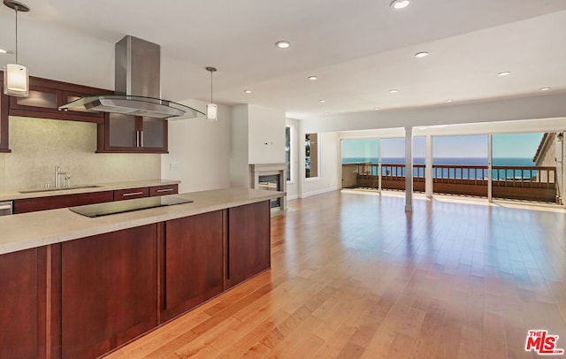 kitchen with pendant lighting, island exhaust hood, light hardwood / wood-style floors, and a water view