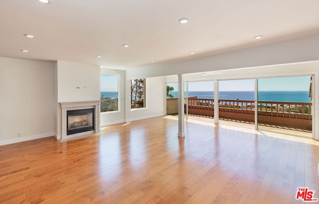 unfurnished living room with light hardwood / wood-style flooring and a water view