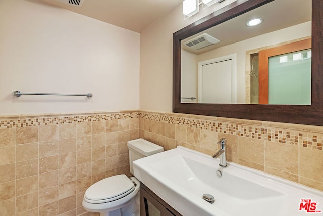 bathroom with tile walls, vanity, and toilet