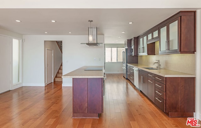 kitchen featuring sink, light hardwood / wood-style flooring, appliances with stainless steel finishes, exhaust hood, and decorative light fixtures