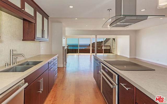 kitchen featuring light wood-type flooring, island range hood, appliances with stainless steel finishes, and sink