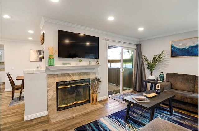 living room featuring hardwood / wood-style flooring, crown molding, and a tiled fireplace