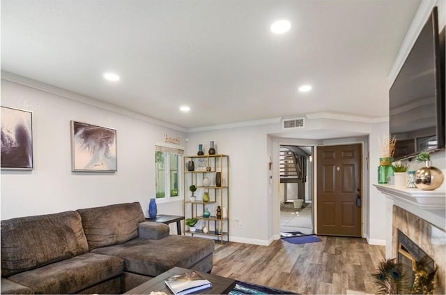 living room with a tile fireplace, crown molding, and hardwood / wood-style floors