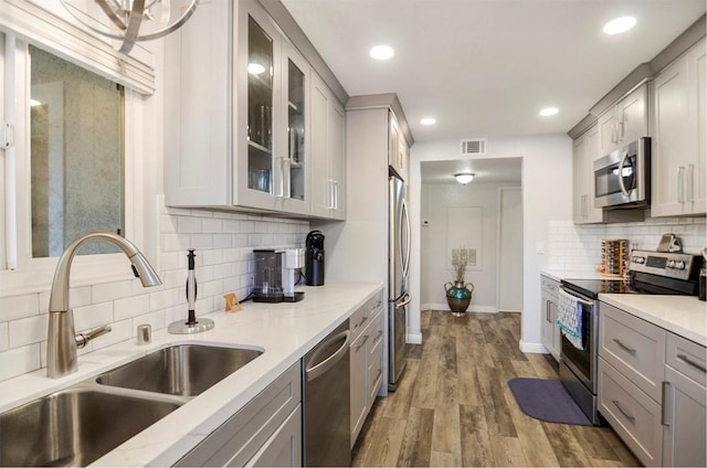 kitchen with appliances with stainless steel finishes, dark hardwood / wood-style flooring, gray cabinets, and sink