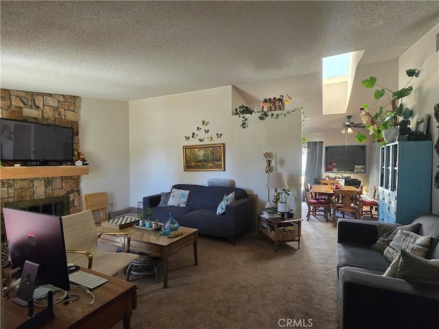 carpeted living room featuring a fireplace, a textured ceiling, a skylight, and ceiling fan