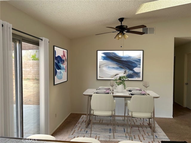 carpeted dining area with vaulted ceiling, ceiling fan, and a textured ceiling