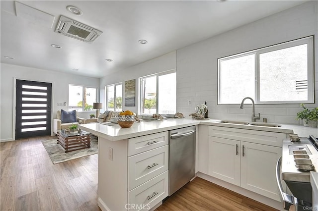 kitchen featuring appliances with stainless steel finishes, light hardwood / wood-style floors, white cabinetry, tasteful backsplash, and kitchen peninsula