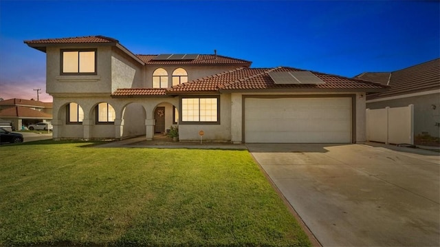 mediterranean / spanish-style home featuring a yard, a garage, and solar panels