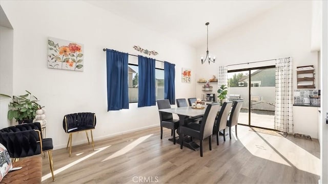 dining area with hardwood / wood-style floors, high vaulted ceiling, and an inviting chandelier