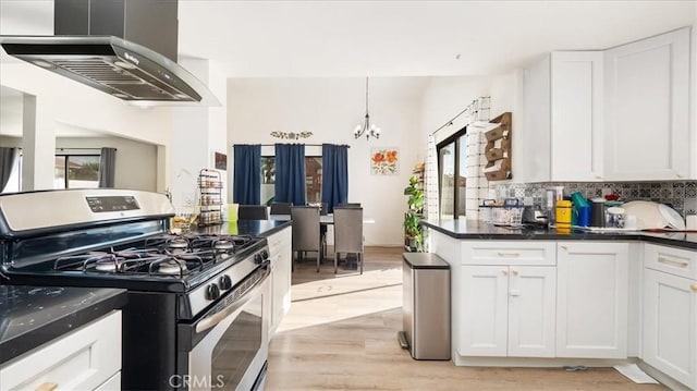 kitchen with backsplash, white cabinets, wall chimney exhaust hood, light hardwood / wood-style floors, and gas stove