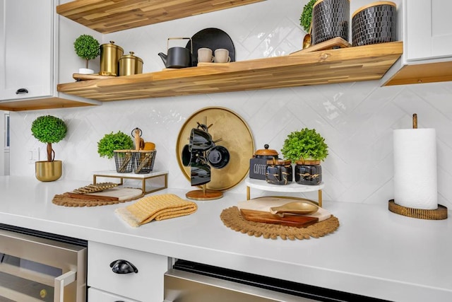 interior details featuring decorative backsplash, beverage cooler, and white cabinets