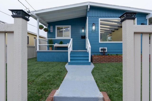 doorway to property featuring covered porch and a lawn