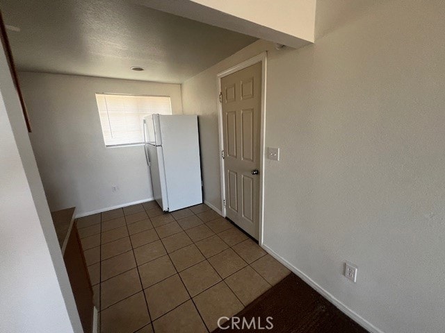 interior space with dark tile patterned flooring and white fridge