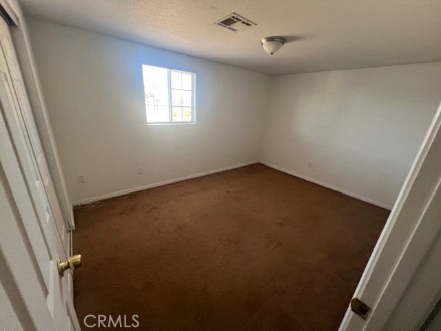 spare room featuring dark colored carpet