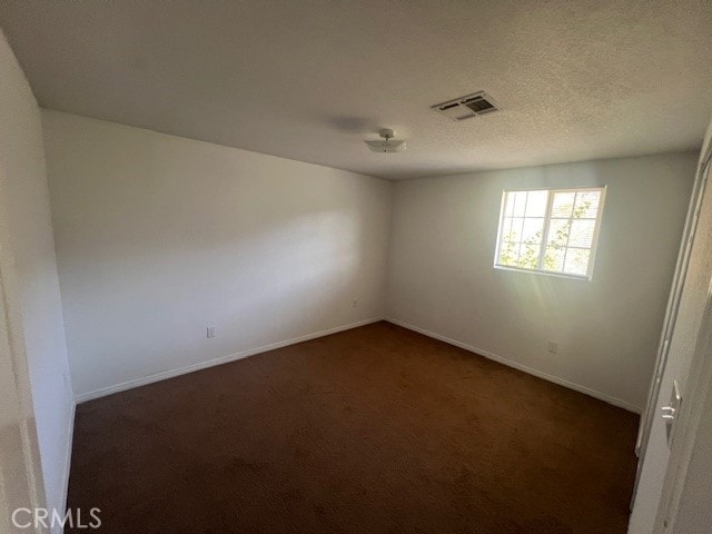 spare room with dark colored carpet