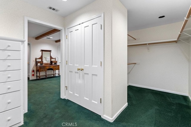 walk in closet featuring beamed ceiling and dark carpet