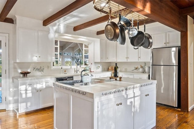 kitchen with a kitchen island, white cabinetry, beam ceiling, hardwood / wood-style flooring, and stainless steel refrigerator