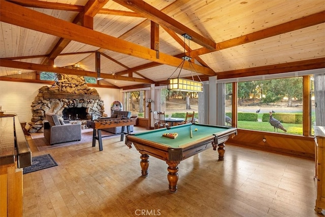 recreation room featuring a stone fireplace, a healthy amount of sunlight, lofted ceiling with beams, and light wood-type flooring