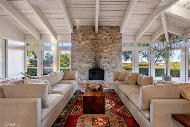 sunroom / solarium featuring vaulted ceiling with beams, a stone fireplace, wooden ceiling, and plenty of natural light