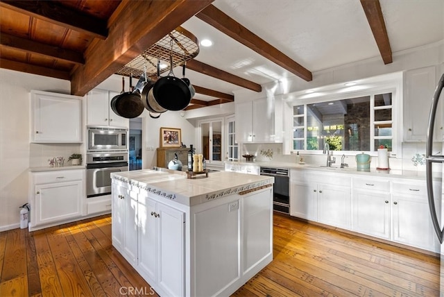 kitchen with stainless steel appliances, light hardwood / wood-style flooring, a kitchen island, and white cabinets