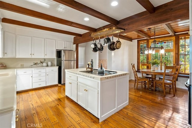 kitchen with a kitchen island, cooktop, white cabinetry, light hardwood / wood-style floors, and stainless steel refrigerator