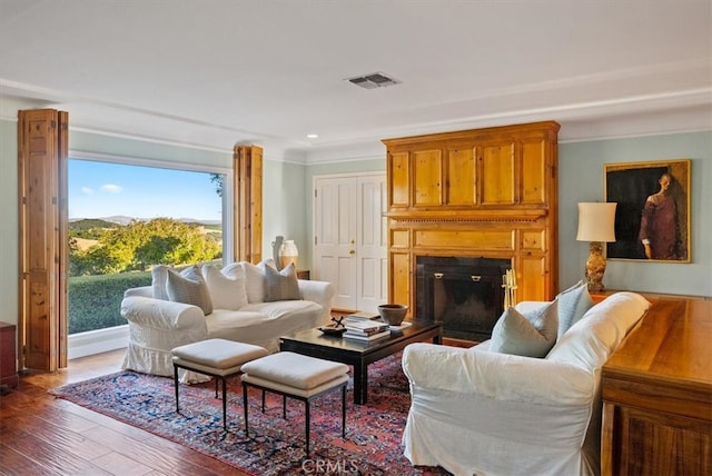 living room featuring crown molding, dark hardwood / wood-style flooring, and a fireplace