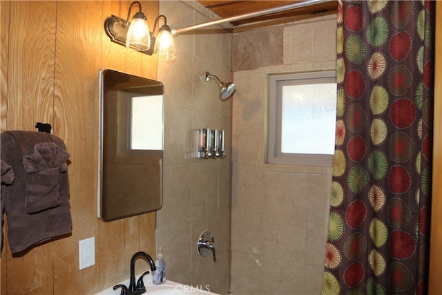 bathroom with curtained shower, wood walls, and a healthy amount of sunlight