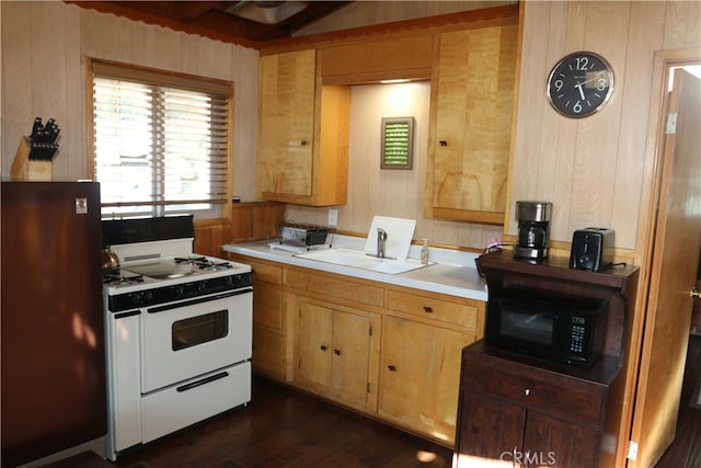 kitchen with fridge, white range, wood walls, and dark wood-type flooring