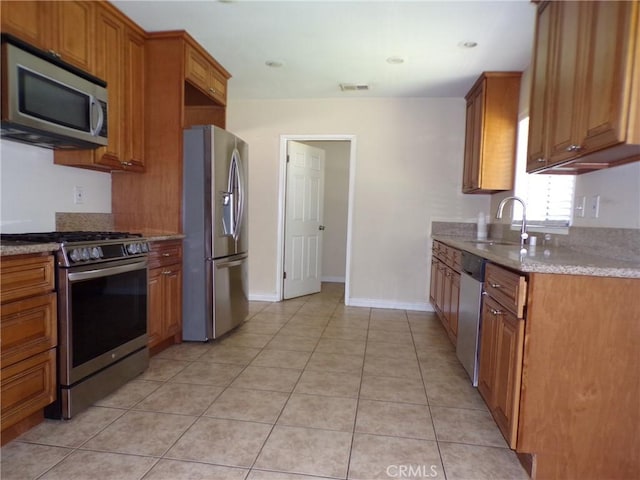 4066 Tenango Rd, Claremont, CA 91711 - kitchen featuring appliances with stainless steel finishes, light tile patterned flooring, a sink, light stone counters, and brown cabinets