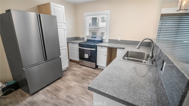 kitchen featuring pendant lighting, light wood-type flooring, sink, white cabinets, and appliances with stainless steel finishes