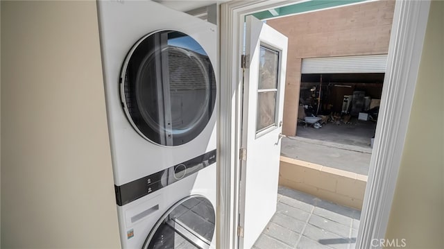 laundry area featuring light tile patterned flooring and stacked washer and dryer