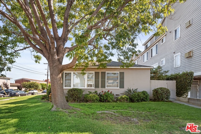 view of front of home featuring a wall mounted air conditioner and a front lawn