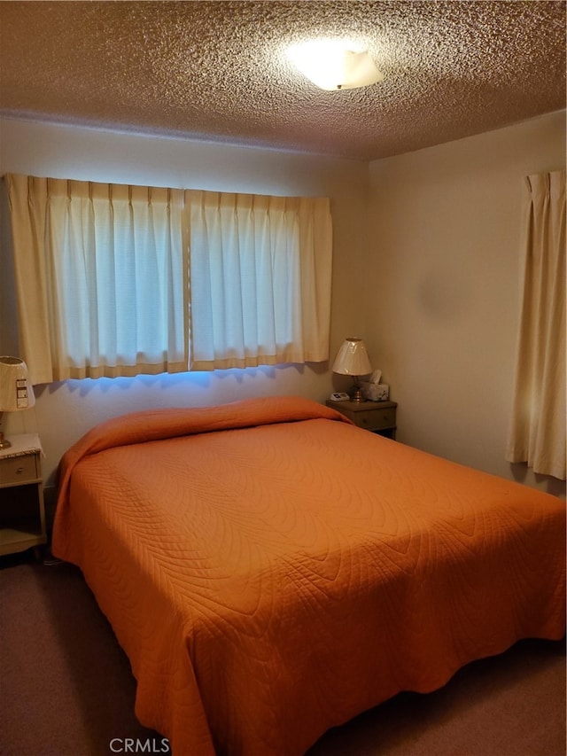 bedroom featuring dark colored carpet and a textured ceiling