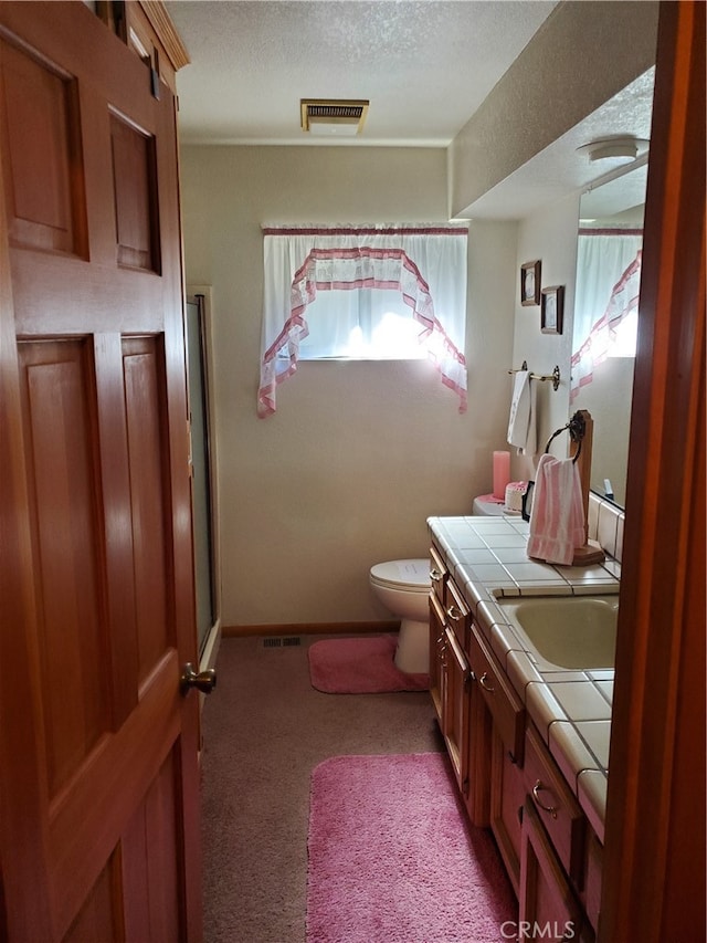 bathroom with walk in shower, vanity, toilet, and a textured ceiling