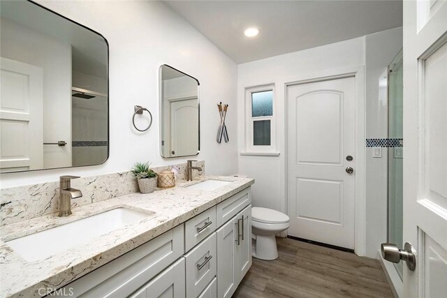 16592 Grimaud Ln, Huntington Beach, CA 92649 - bathroom with double vanity, wood finished floors, toilet, a shower, and recessed lighting